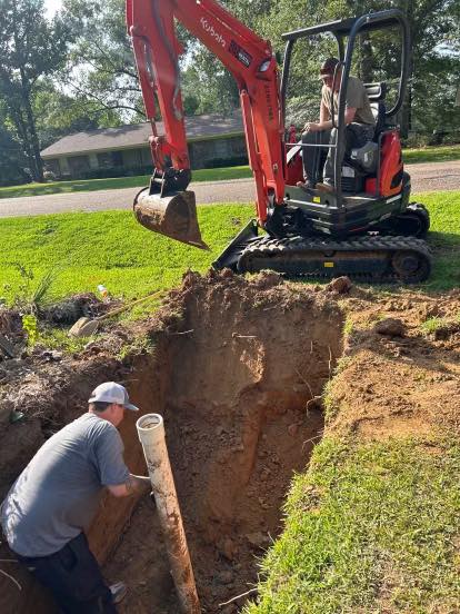 Two-person crew setting a sewer line with an excavator